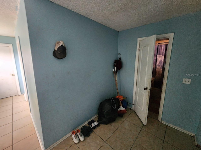 hallway featuring a textured ceiling and light tile patterned flooring