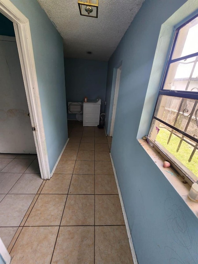 hall with light tile patterned flooring and a textured ceiling