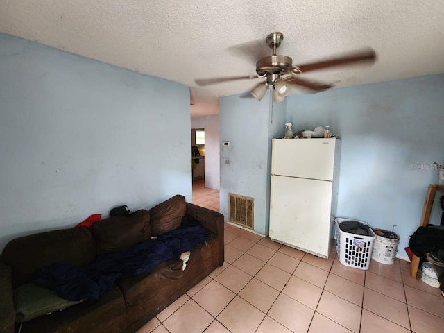 tiled living room with ceiling fan and a textured ceiling