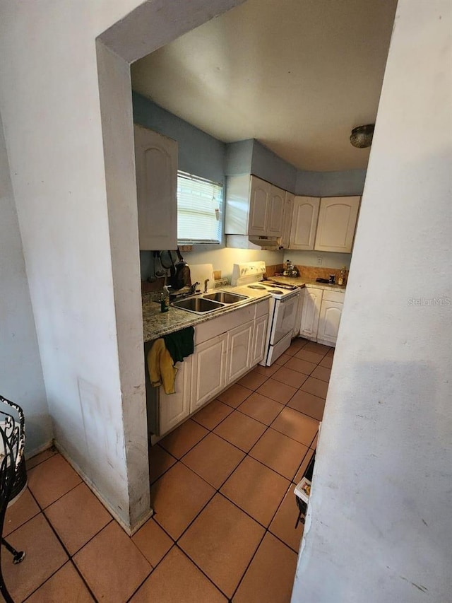 kitchen with white electric range, light tile patterned flooring, and sink