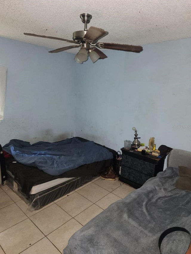 bedroom featuring ceiling fan, light tile patterned flooring, and a textured ceiling