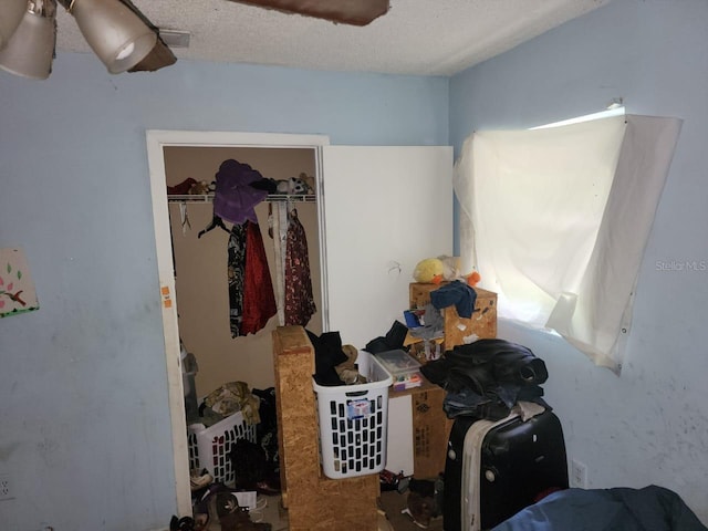 bedroom with a textured ceiling, ceiling fan, and a closet