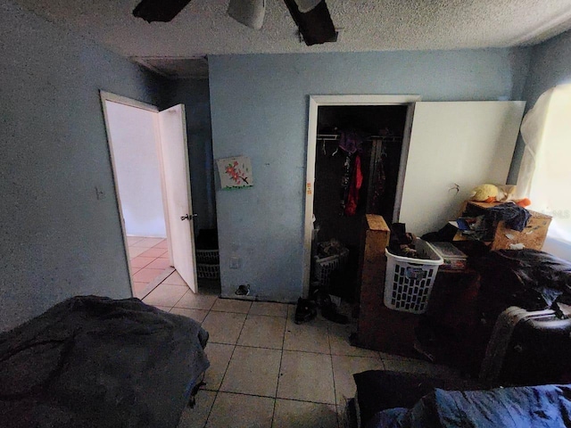 bedroom featuring a closet, ceiling fan, a textured ceiling, and light tile patterned flooring