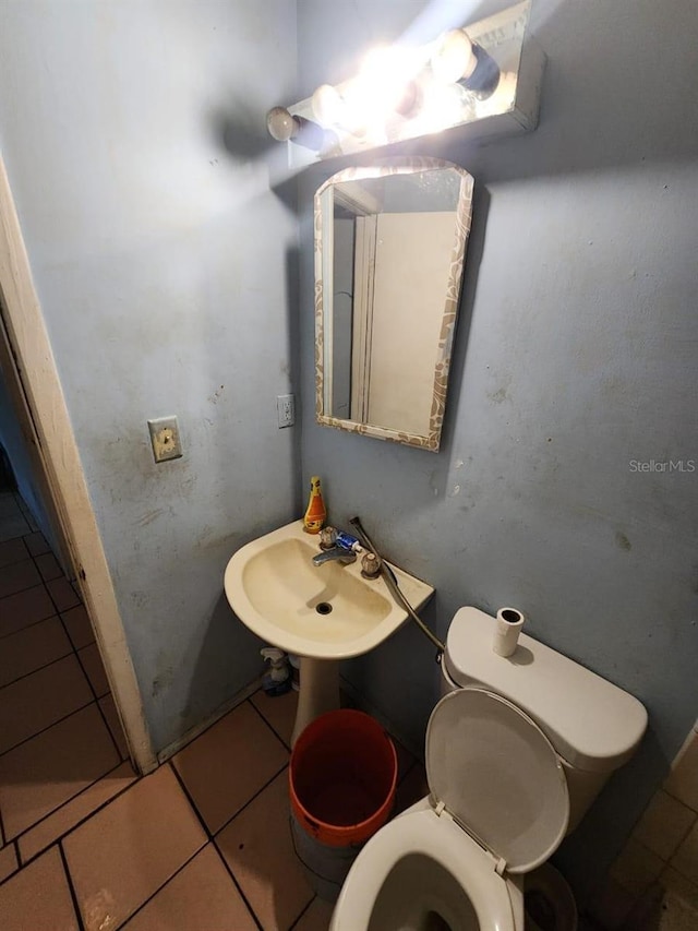 bathroom featuring toilet, sink, and tile patterned flooring