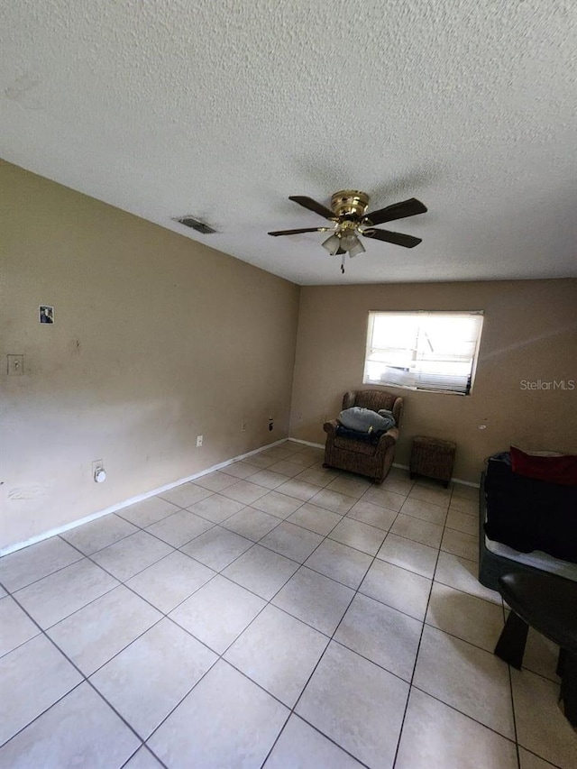 unfurnished living room featuring a textured ceiling, ceiling fan, and light tile patterned floors