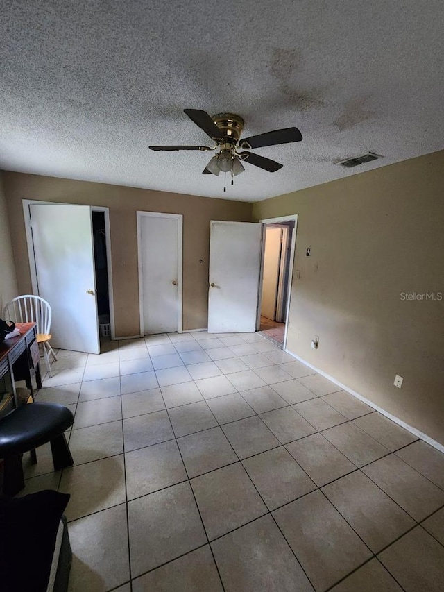 unfurnished bedroom with a textured ceiling, ceiling fan, and light tile patterned floors