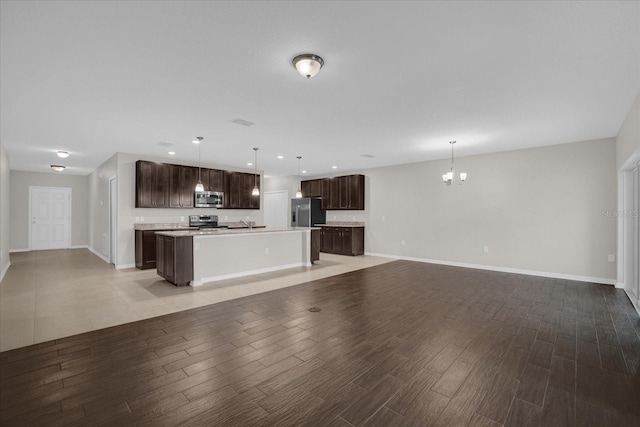 8064 Olive Brook Dr, Wesley Chapel, FL 33545 - kitchen featuring light wood finished floors, an island with sink, dark brown cabinetry, appliances with stainless steel finishes, and open floor plan