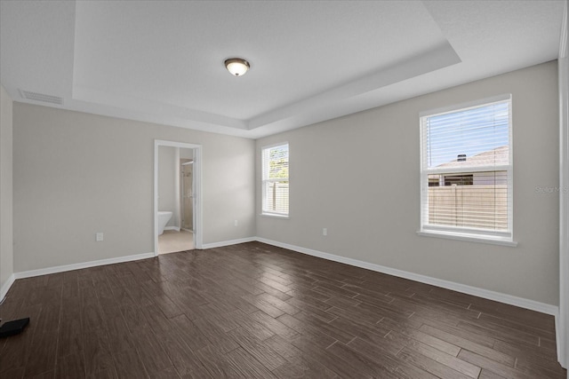 8064 Olive Brook Dr, Wesley Chapel, FL 33545 - spare room with visible vents, baseboards, a tray ceiling, and dark wood-style flooring