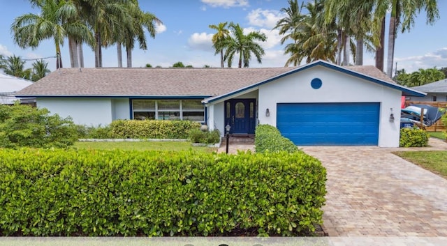 ranch-style house with decorative driveway, an attached garage, and stucco siding