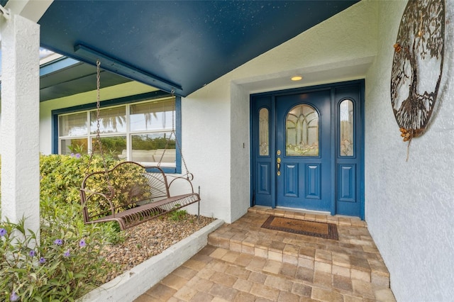 entrance to property with a porch and stucco siding