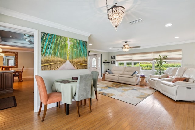 dining area with crown molding, ceiling fan with notable chandelier, and light hardwood / wood-style floors