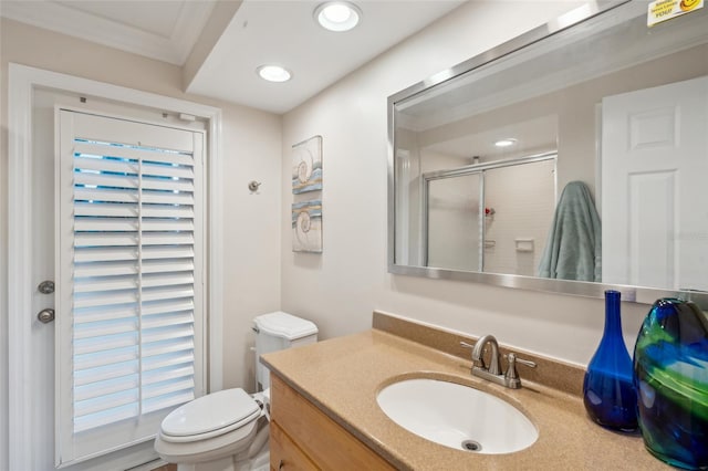 bathroom featuring crown molding, vanity, toilet, and a shower with door