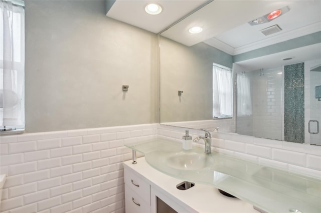 bathroom with crown molding, vanity, tile walls, and a shower with door