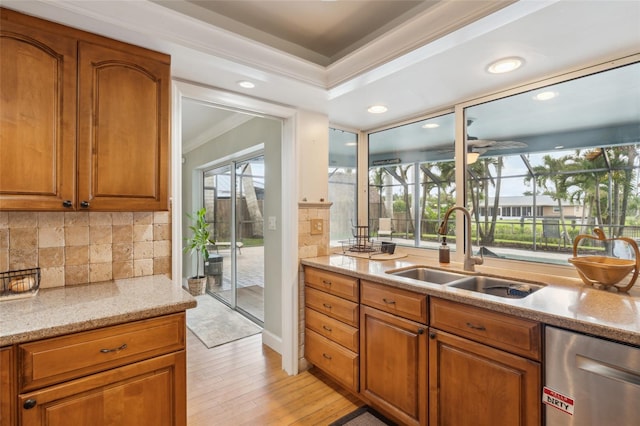 kitchen featuring light wood-type flooring, plenty of natural light, light stone counters, and sink