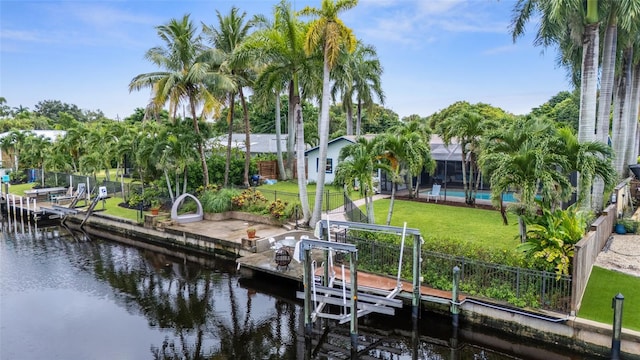 dock area featuring a swimming pool, glass enclosure, a water view, and a yard