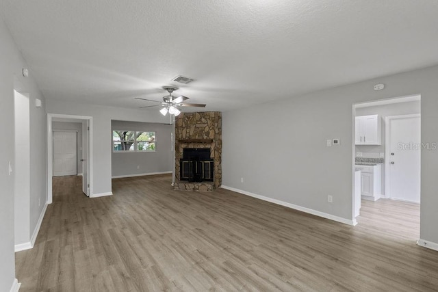 unfurnished living room with a fireplace, a textured ceiling, hardwood / wood-style floors, and ceiling fan