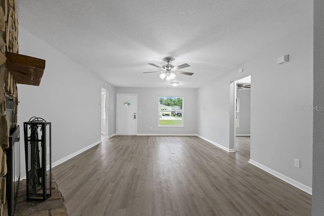 unfurnished living room with ceiling fan, dark hardwood / wood-style floors, and a textured ceiling