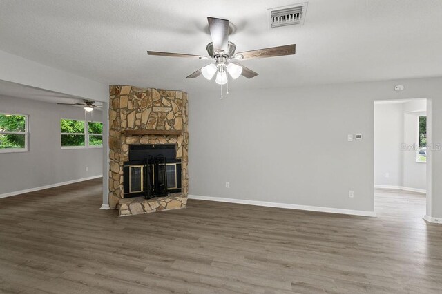 unfurnished living room featuring ceiling fan, a stone fireplace, and hardwood / wood-style flooring