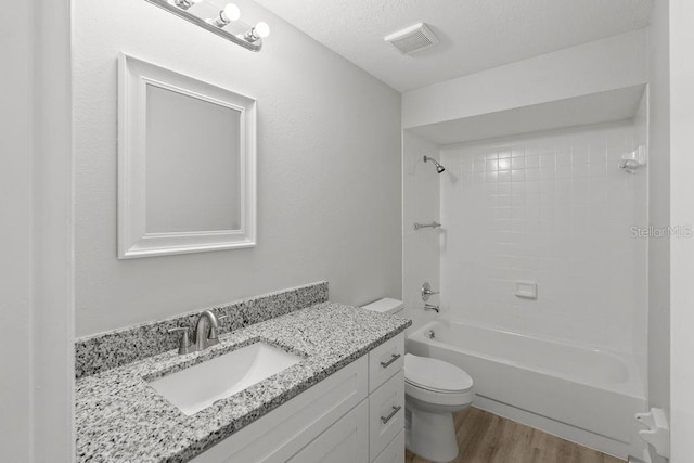 full bathroom featuring shower / bathtub combination, hardwood / wood-style floors, toilet, vanity, and a textured ceiling