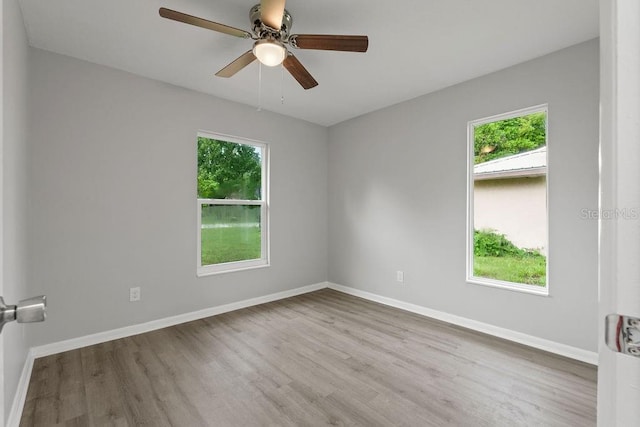 empty room featuring a wealth of natural light, ceiling fan, and hardwood / wood-style flooring