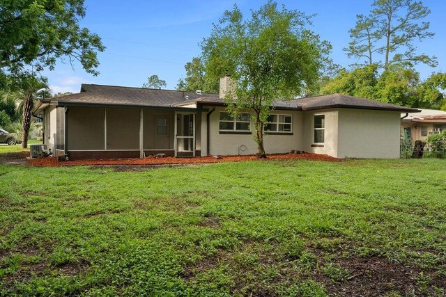 rear view of property with a yard, cooling unit, and a sunroom