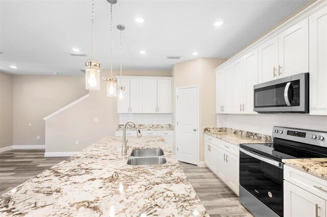 kitchen featuring decorative light fixtures, appliances with stainless steel finishes, white cabinetry, and sink