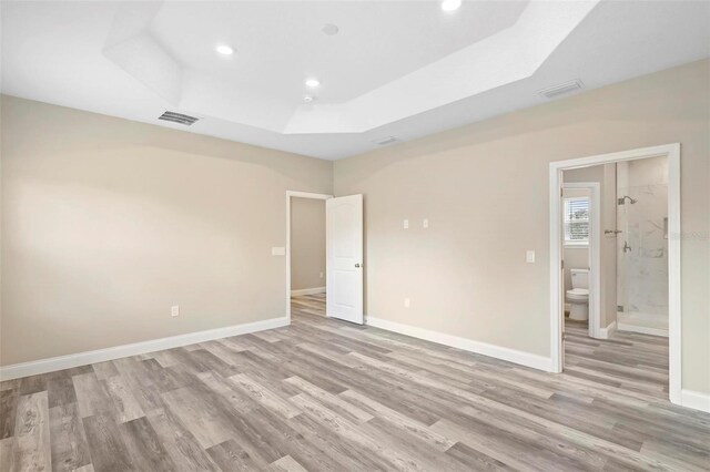 unfurnished room featuring a raised ceiling and light hardwood / wood-style flooring