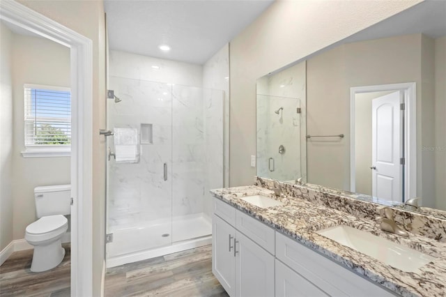 bathroom with hardwood / wood-style floors, toilet, a shower with door, and vanity