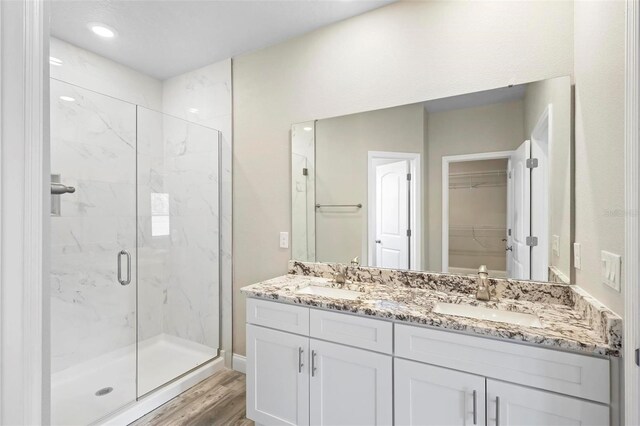 bathroom with a shower with shower door, hardwood / wood-style floors, and vanity