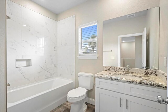 full bathroom featuring tiled shower / bath, vanity, toilet, and hardwood / wood-style floors