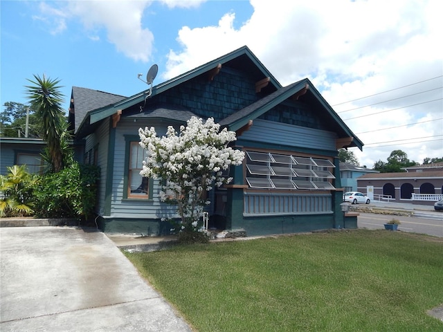 view of front of home featuring a front lawn and roof with shingles