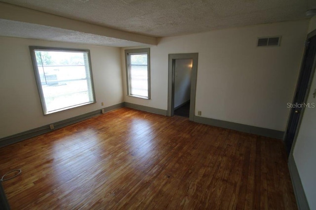 empty room with dark wood-type flooring and a textured ceiling