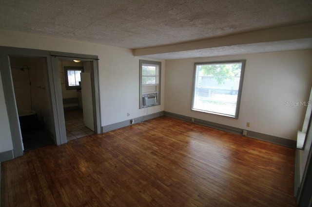 unfurnished bedroom featuring cooling unit, a textured ceiling, baseboards, and wood finished floors