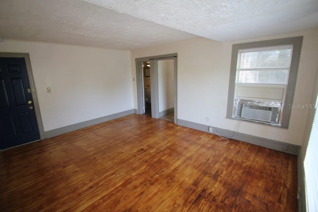 empty room featuring a textured ceiling, hardwood / wood-style floors, and cooling unit