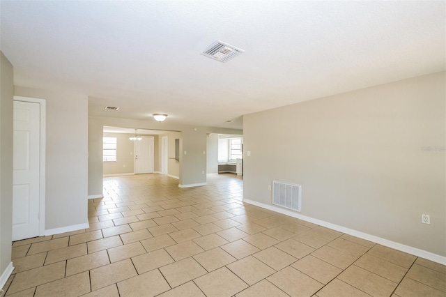 unfurnished room featuring light tile patterned flooring, baseboards, visible vents, and a chandelier