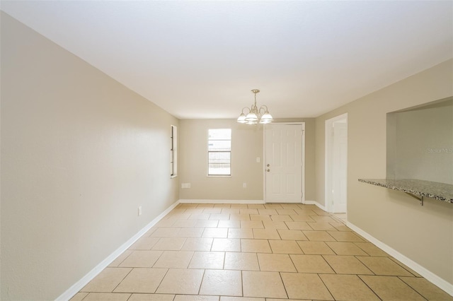 empty room with an inviting chandelier and baseboards