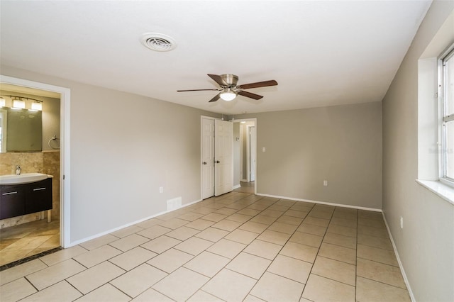 unfurnished bedroom featuring ceiling fan, sink, ensuite bath, and light tile patterned flooring