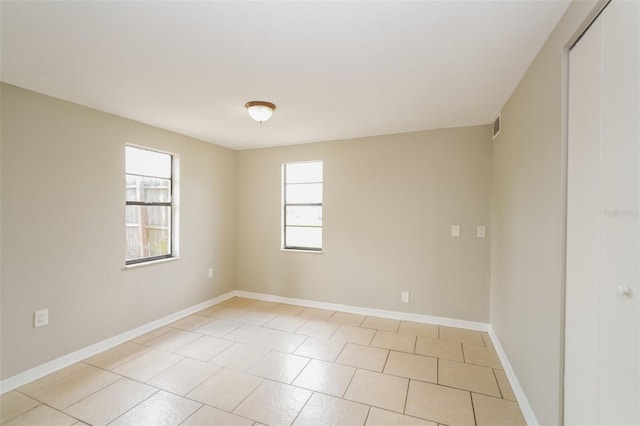 spare room with light tile patterned flooring, visible vents, and baseboards