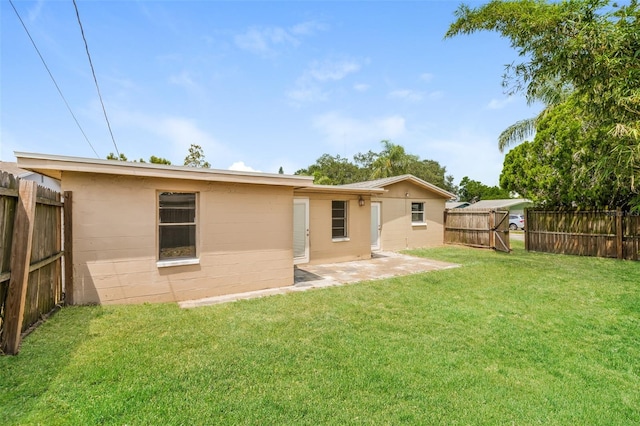 rear view of house featuring a fenced backyard, a patio area, and a yard