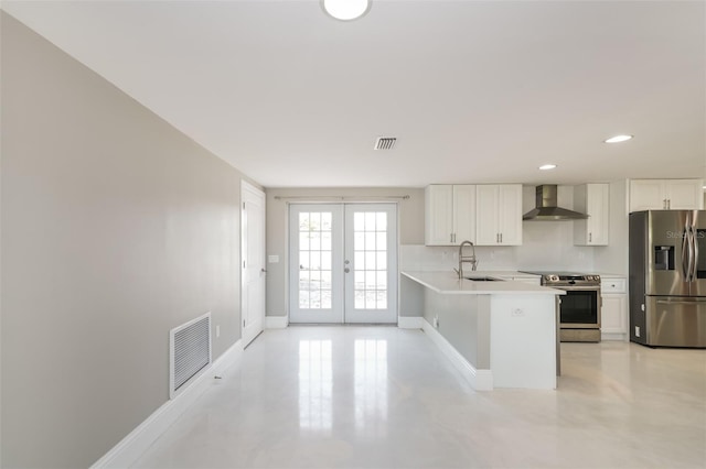 kitchen with stainless steel appliances, sink, kitchen peninsula, white cabinetry, and wall chimney range hood