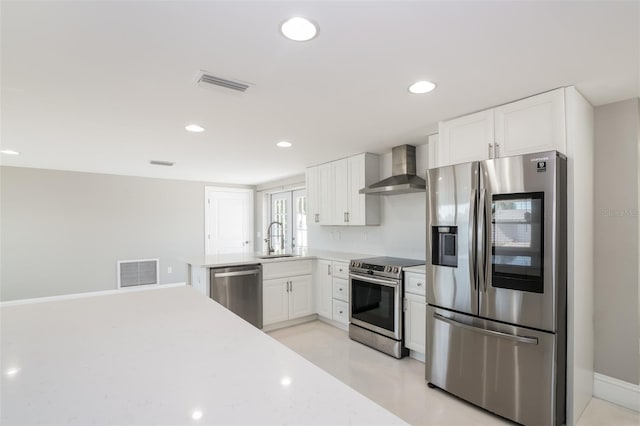 kitchen with wall chimney exhaust hood, appliances with stainless steel finishes, sink, and white cabinets