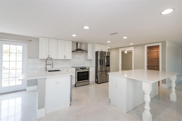 kitchen featuring white cabinets, appliances with stainless steel finishes, sink, wall chimney range hood, and tasteful backsplash