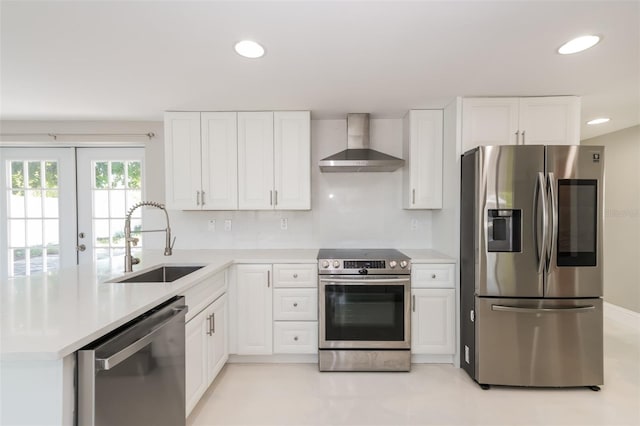 kitchen with appliances with stainless steel finishes, sink, white cabinets, and wall chimney range hood