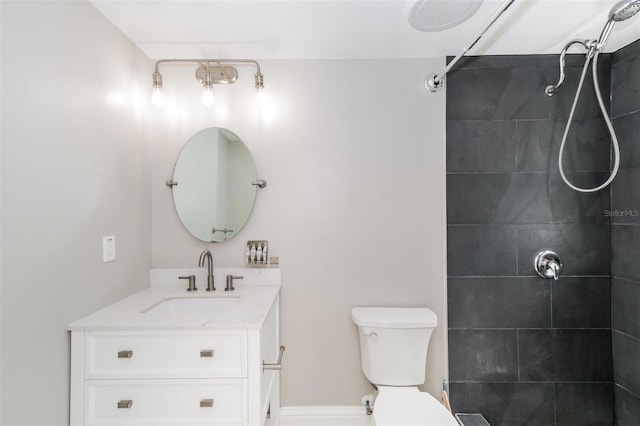 bathroom featuring vanity, toilet, and a tile shower