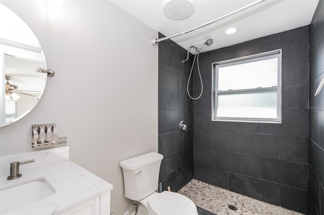 bathroom featuring a wealth of natural light, vanity, toilet, and a tile shower