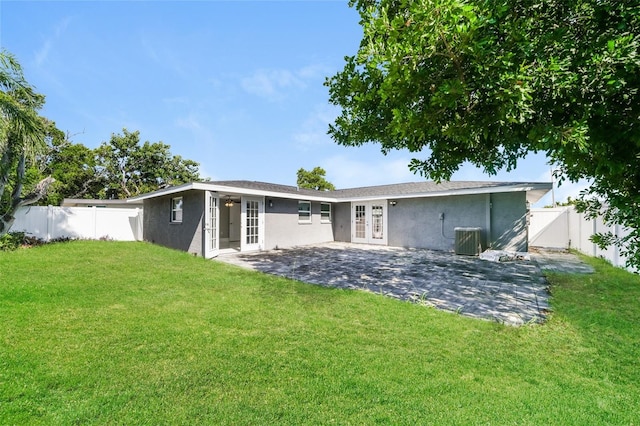 back of property with cooling unit, french doors, a yard, and a patio area