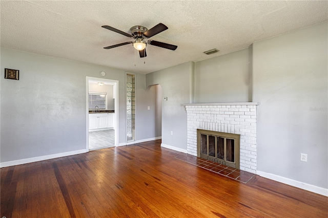 unfurnished living room featuring a fireplace, ceiling fan, a textured ceiling, and dark hardwood / wood-style flooring