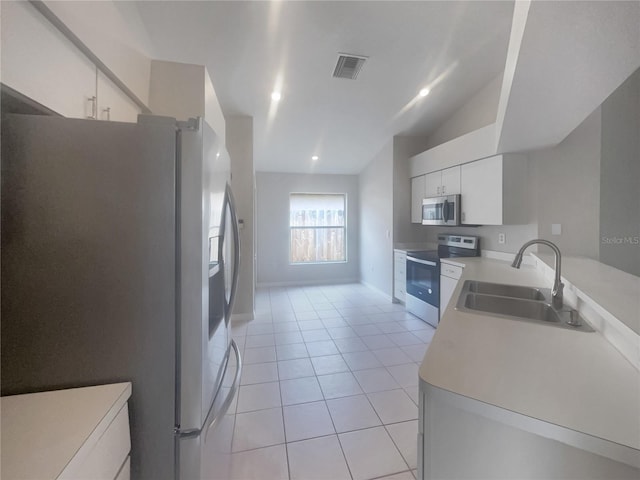 kitchen with light tile patterned floors, stainless steel appliances, sink, white cabinetry, and lofted ceiling