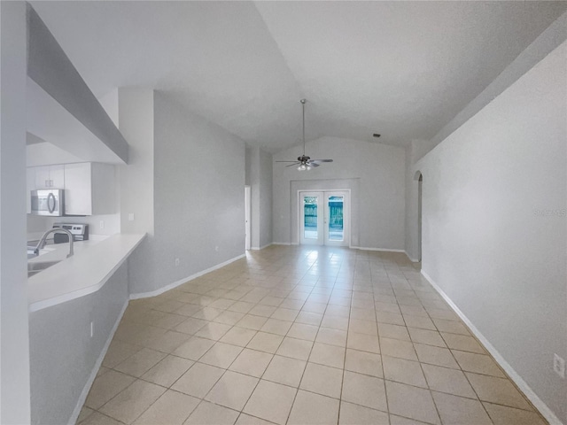 unfurnished living room with lofted ceiling, ceiling fan, sink, and light tile patterned floors