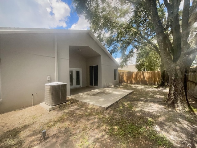 rear view of property with french doors, cooling unit, and a patio